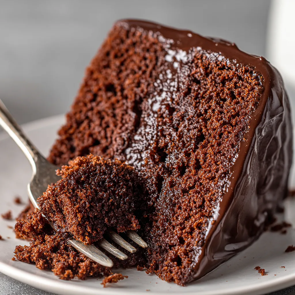 Nahaufnahme eines Stücks saftigen Schokoladenkuchens mit lockerer Krume und Schokoladenglasur
